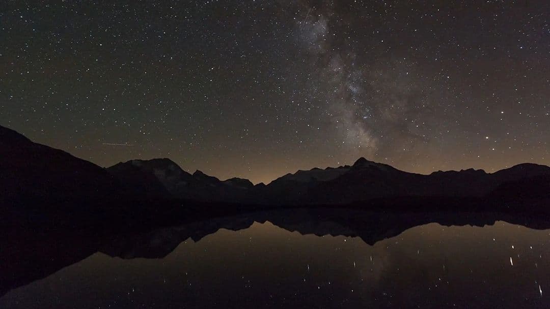 The Milky Way over mountains reflected in a still lake